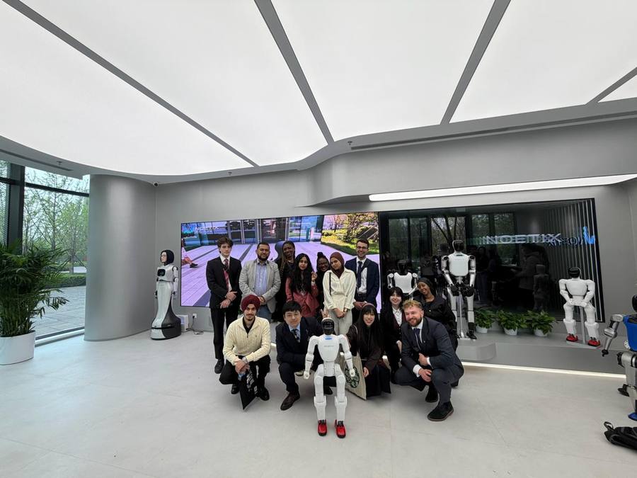 Delegation group photo at NOETIX robotics AI startup showroom in China, with humanoid robots on display